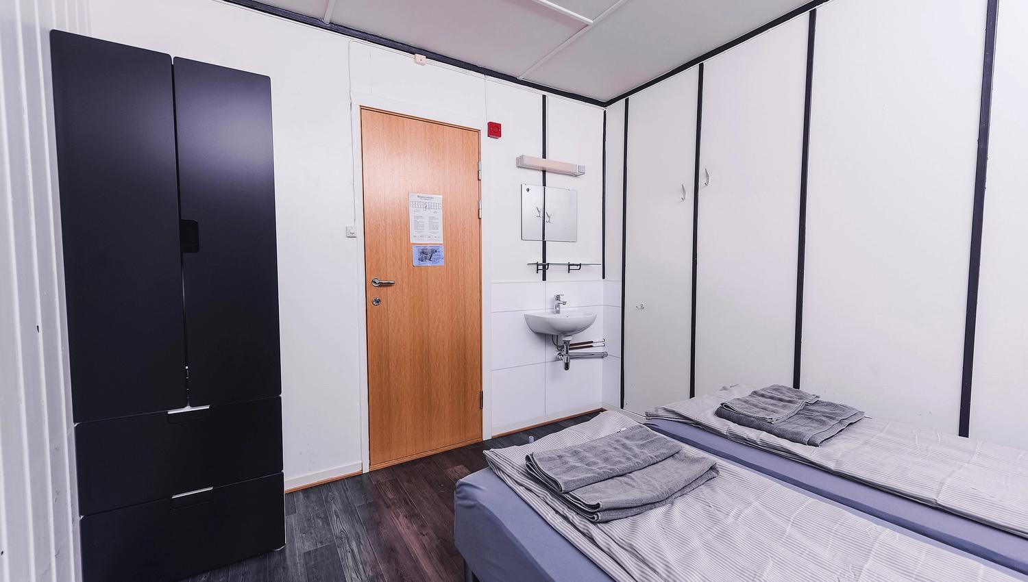 A bedroom with two beds, a closet and a sink.