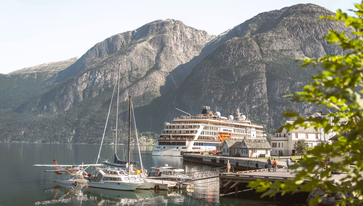 The harbour area with a cruise ship, a couple of sail boats, a seaplane and people on the dock.