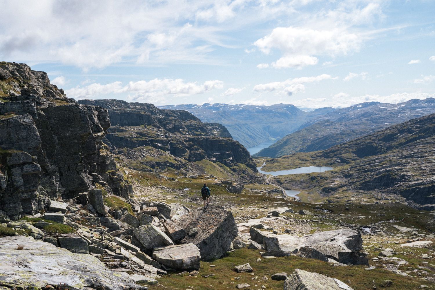 Person står på fjellformasjon og ser utover fjellandskapet.