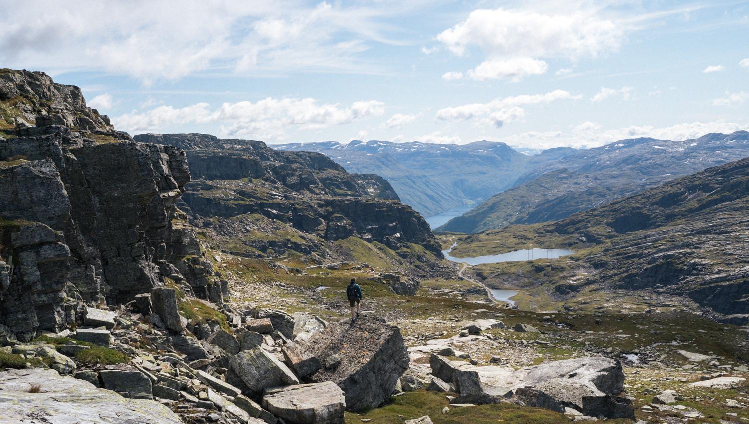 Person står på fjellformasjon og ser utover fjellandskapet.