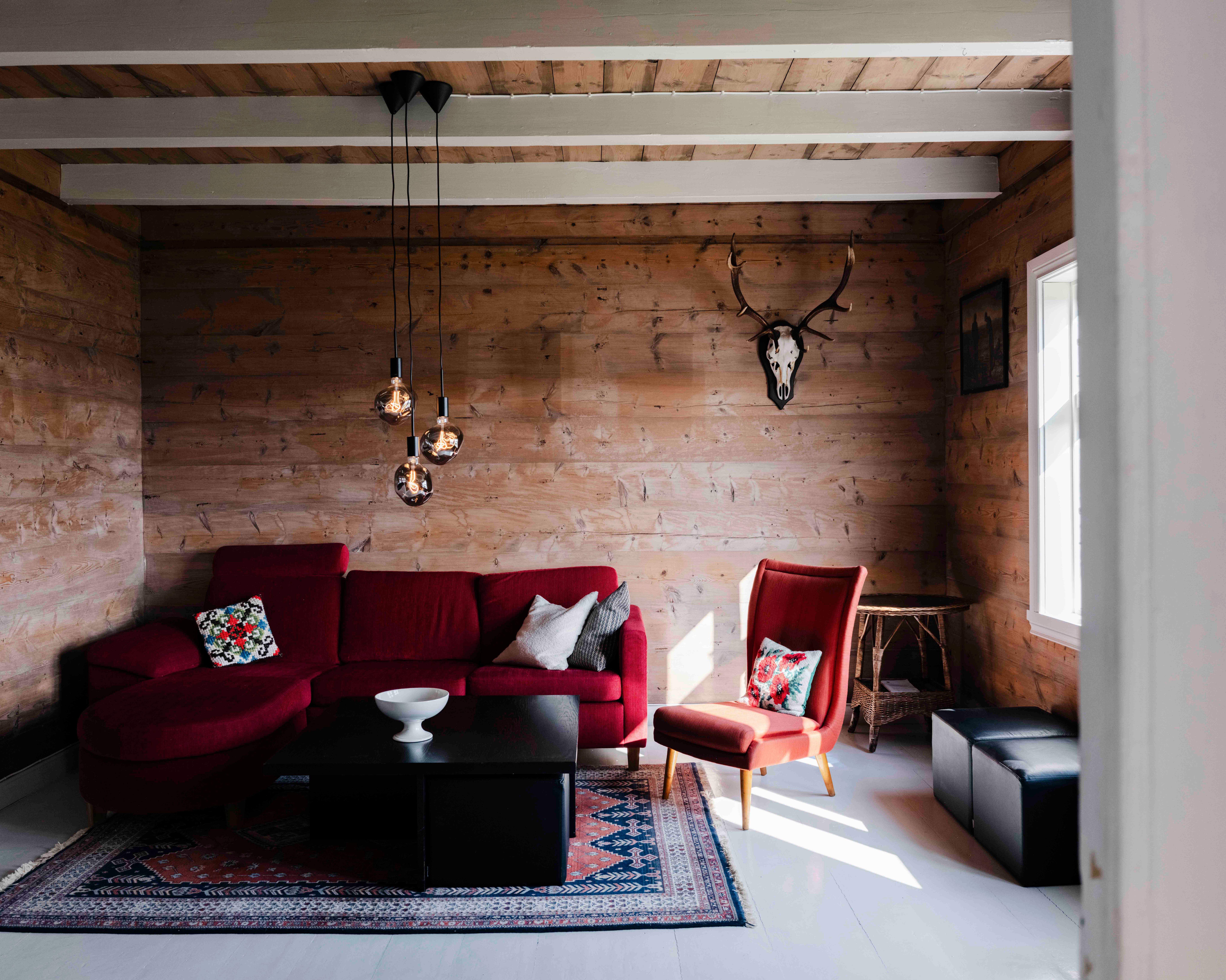 Cozy living room at Stigen Fjordlodge with a red sofa and warm Scandinavian interior.