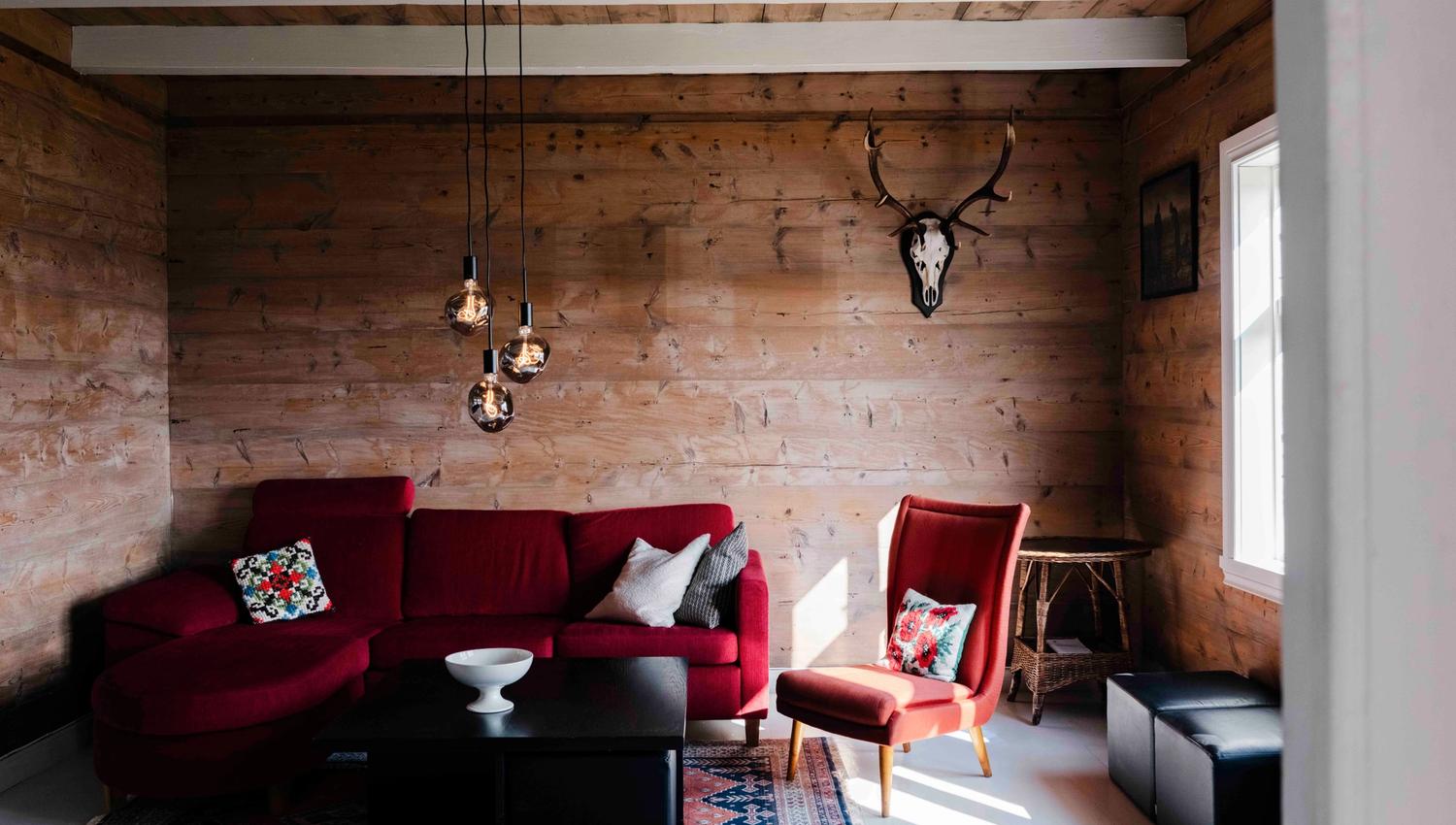 Cozy living room at Stigen Fjordlodge with a red sofa and warm Scandinavian interior.