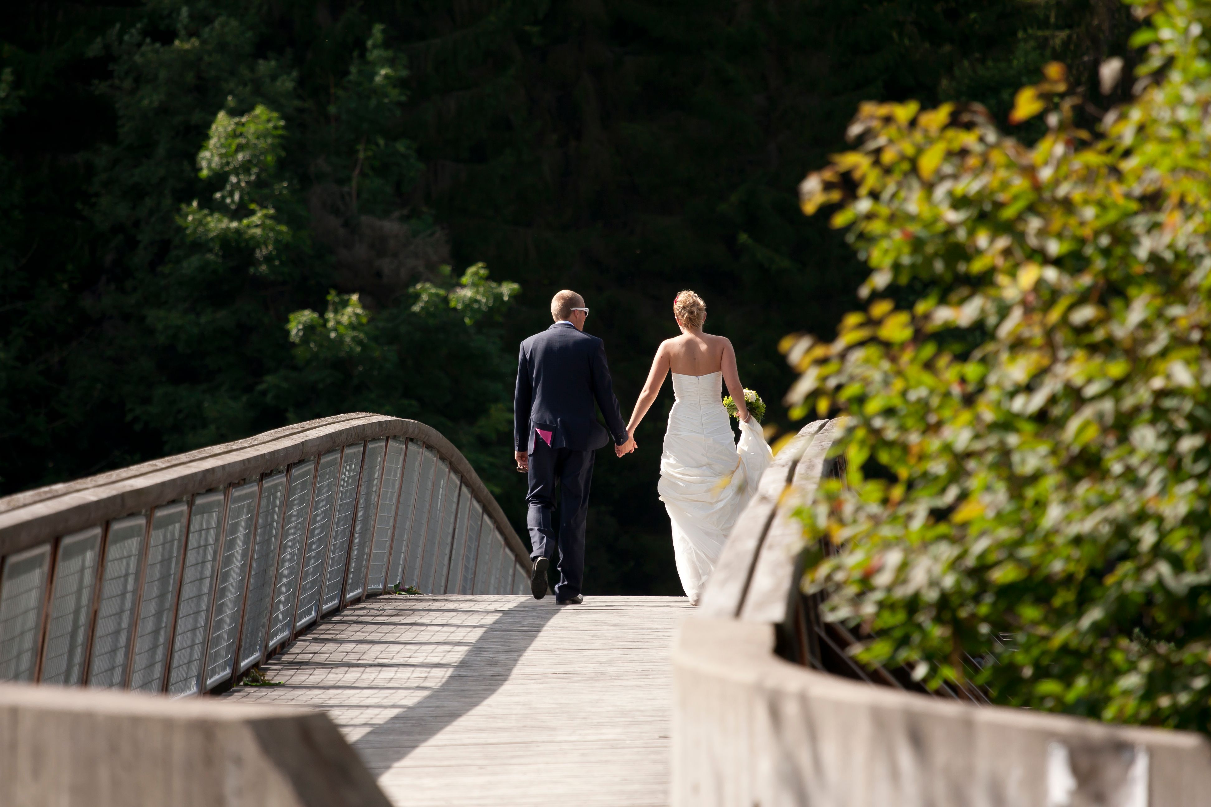 Bride and groom walk across the bridge in Kjærra Fossepark