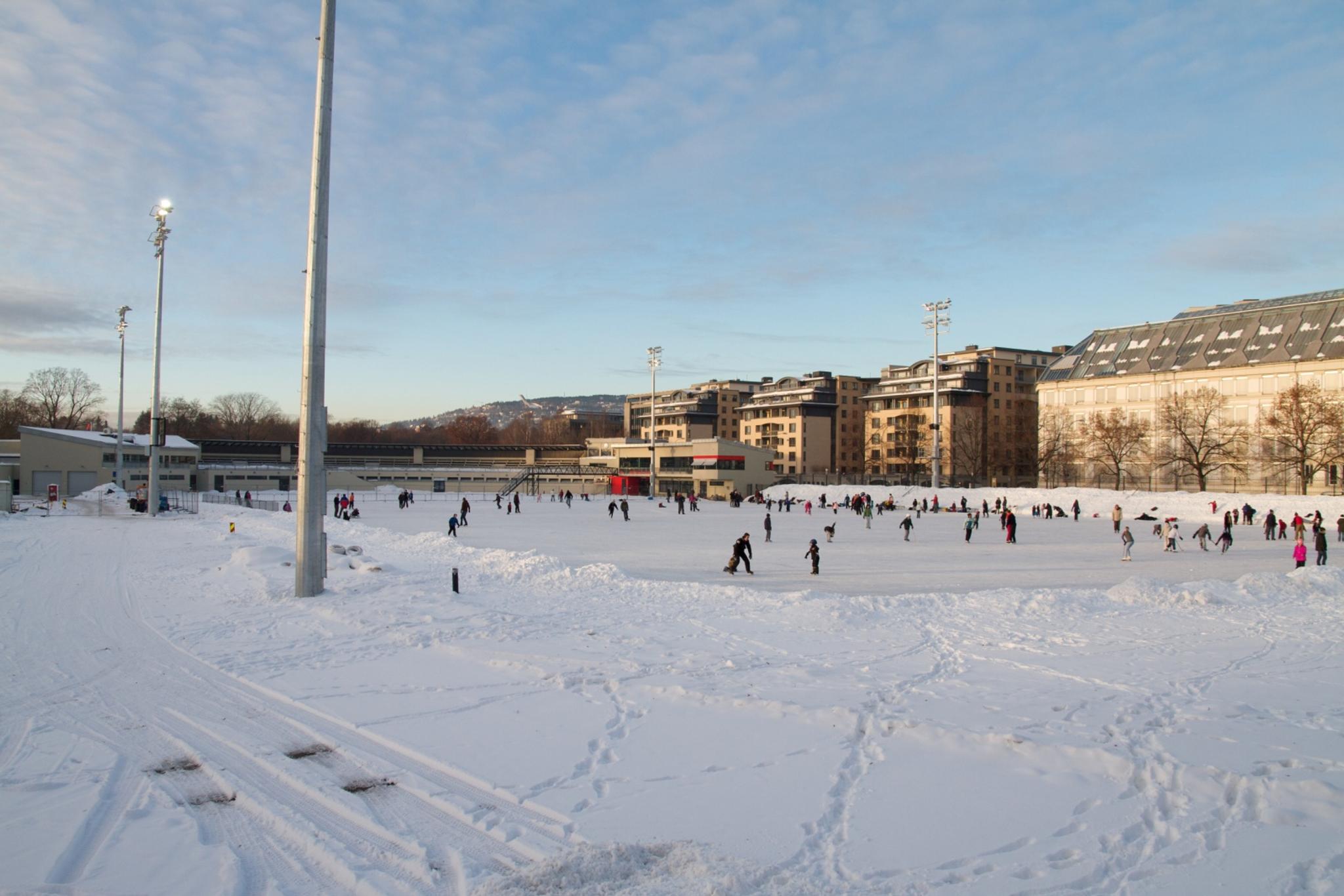 Snødekt skøytebane med mennesker som står på skøyter.