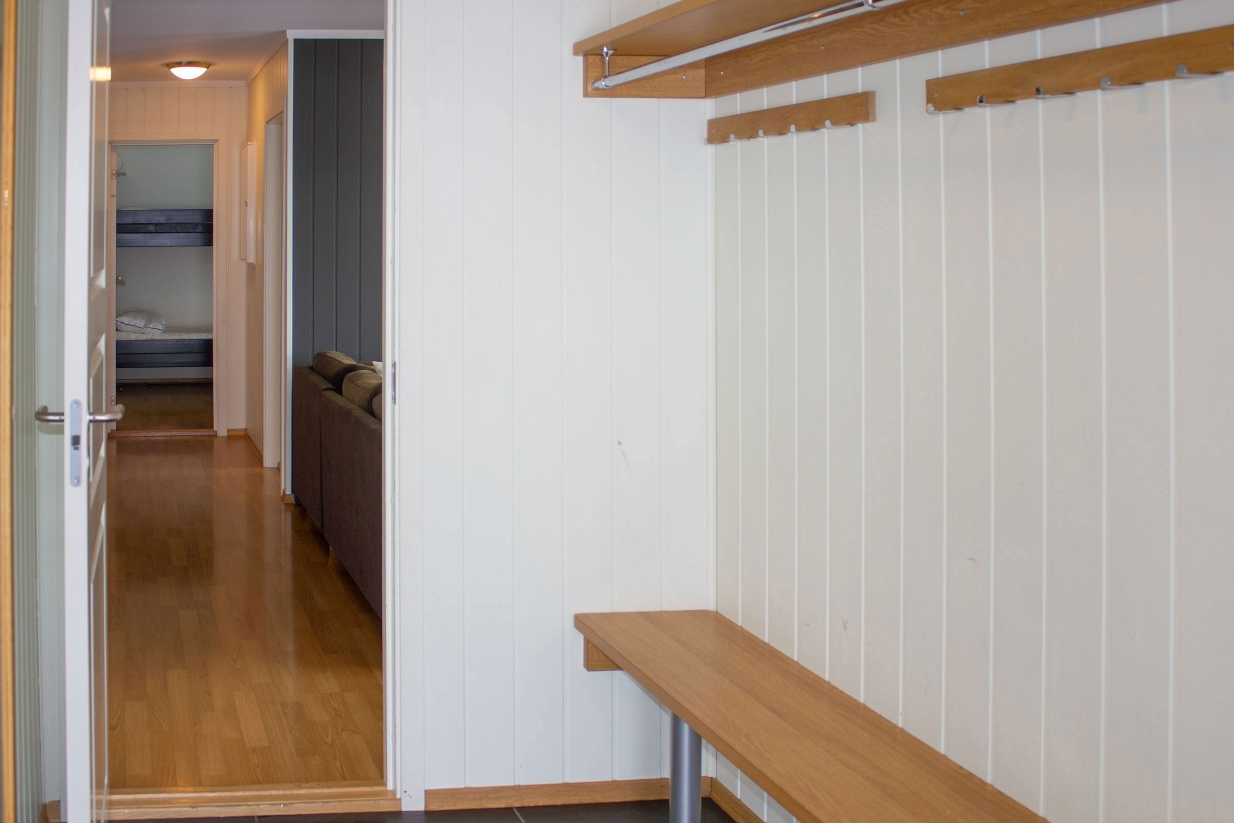 A hallway with a bench and clothes rack.