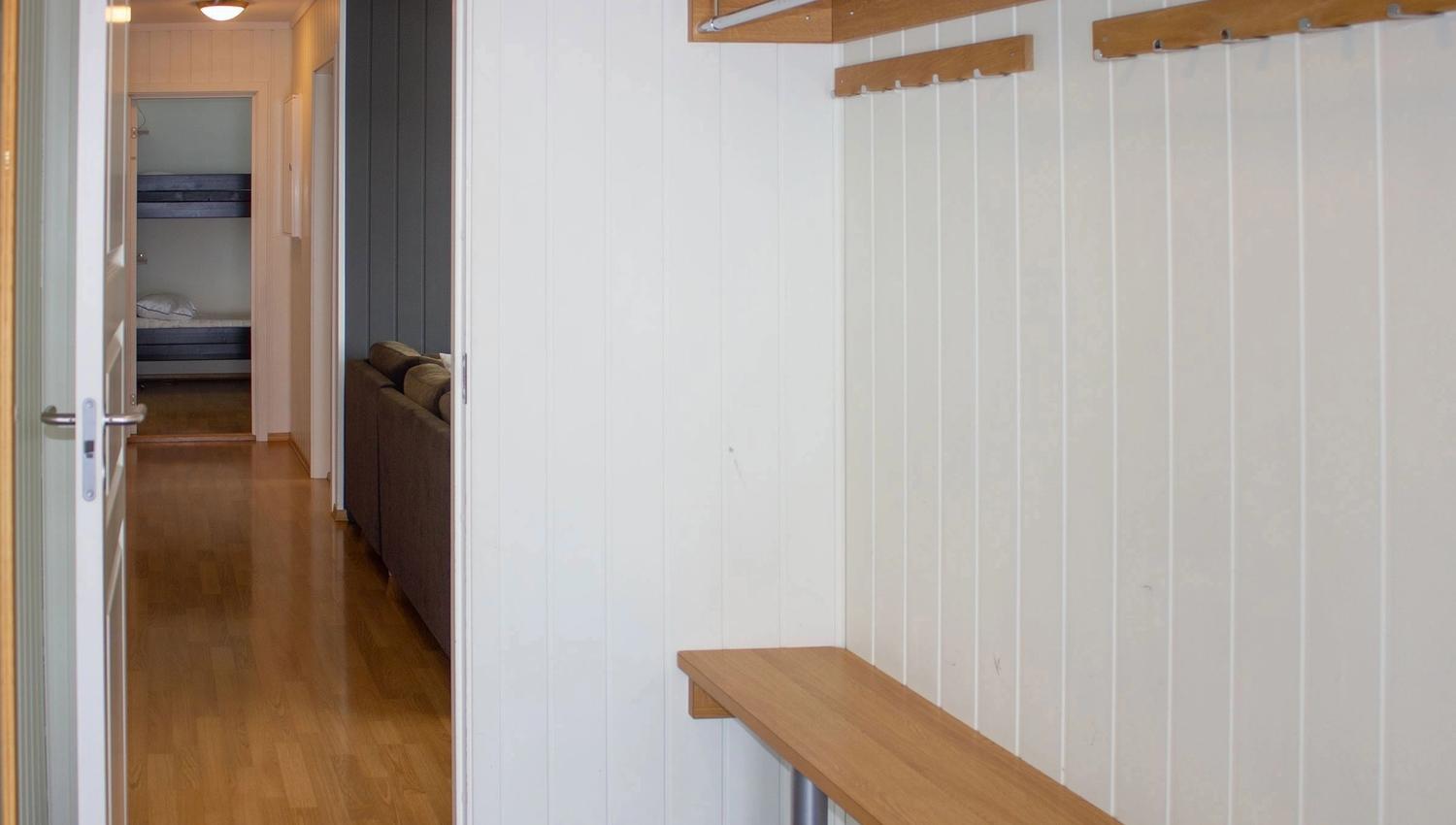 A hallway with a bench and clothes rack.