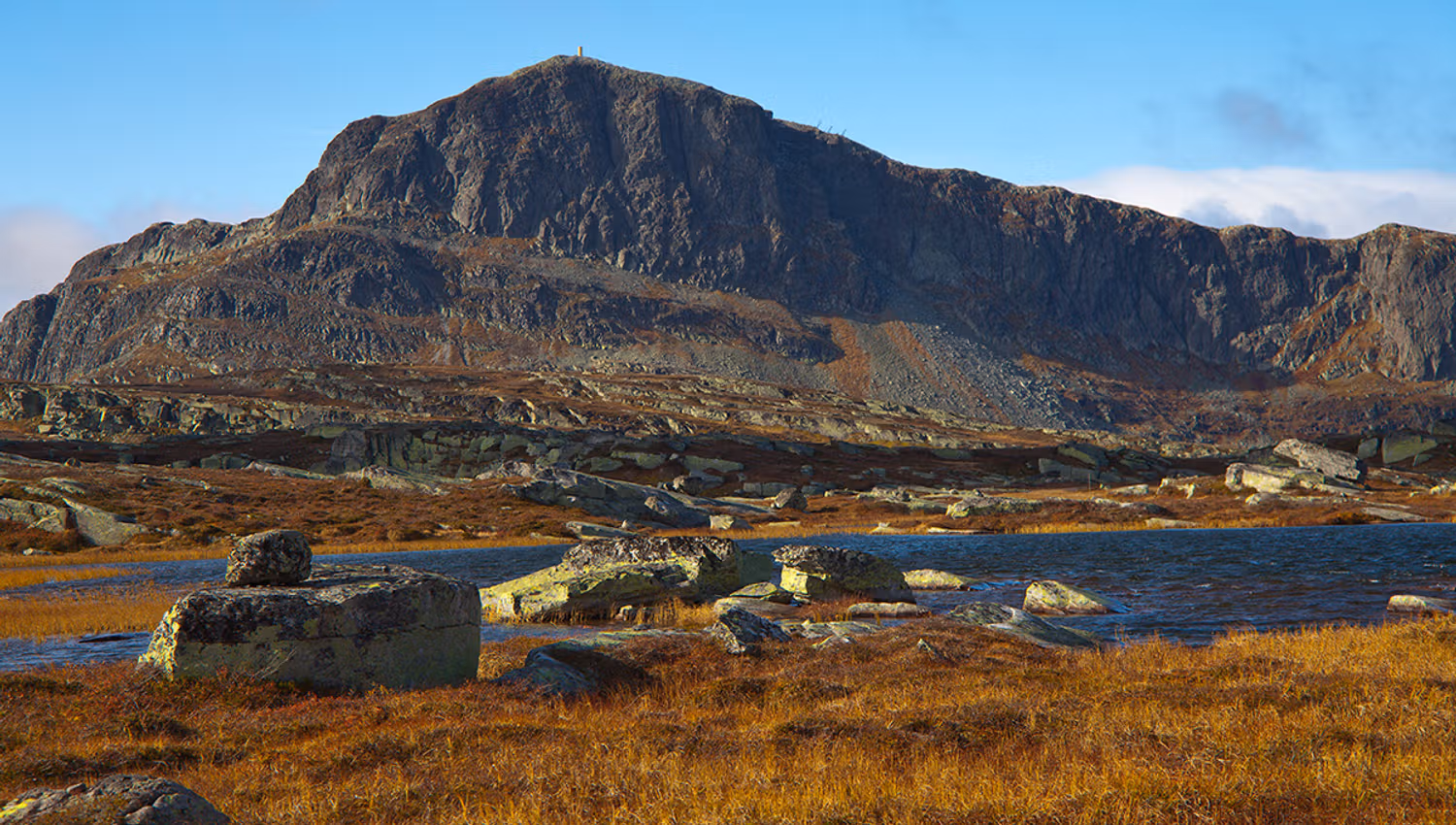 Bitihorn shows its rough side with its steep east face to the photogapher. In the foreground some small lakes and lichen-covered rocks.