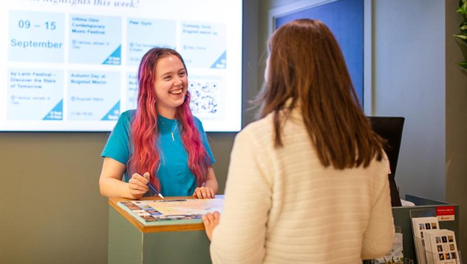 Smiling employee in the tourist information helping a customer