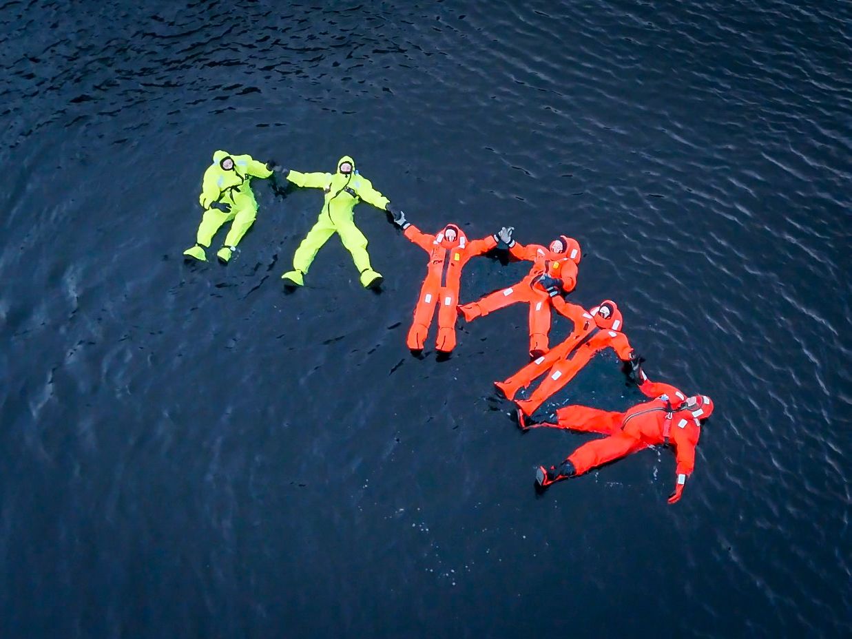 People floating in the Hardangerfjord in immersion suits