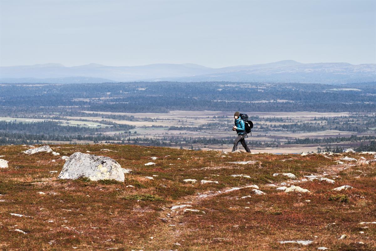 Person walking along a mountain ridge with views of valley and water