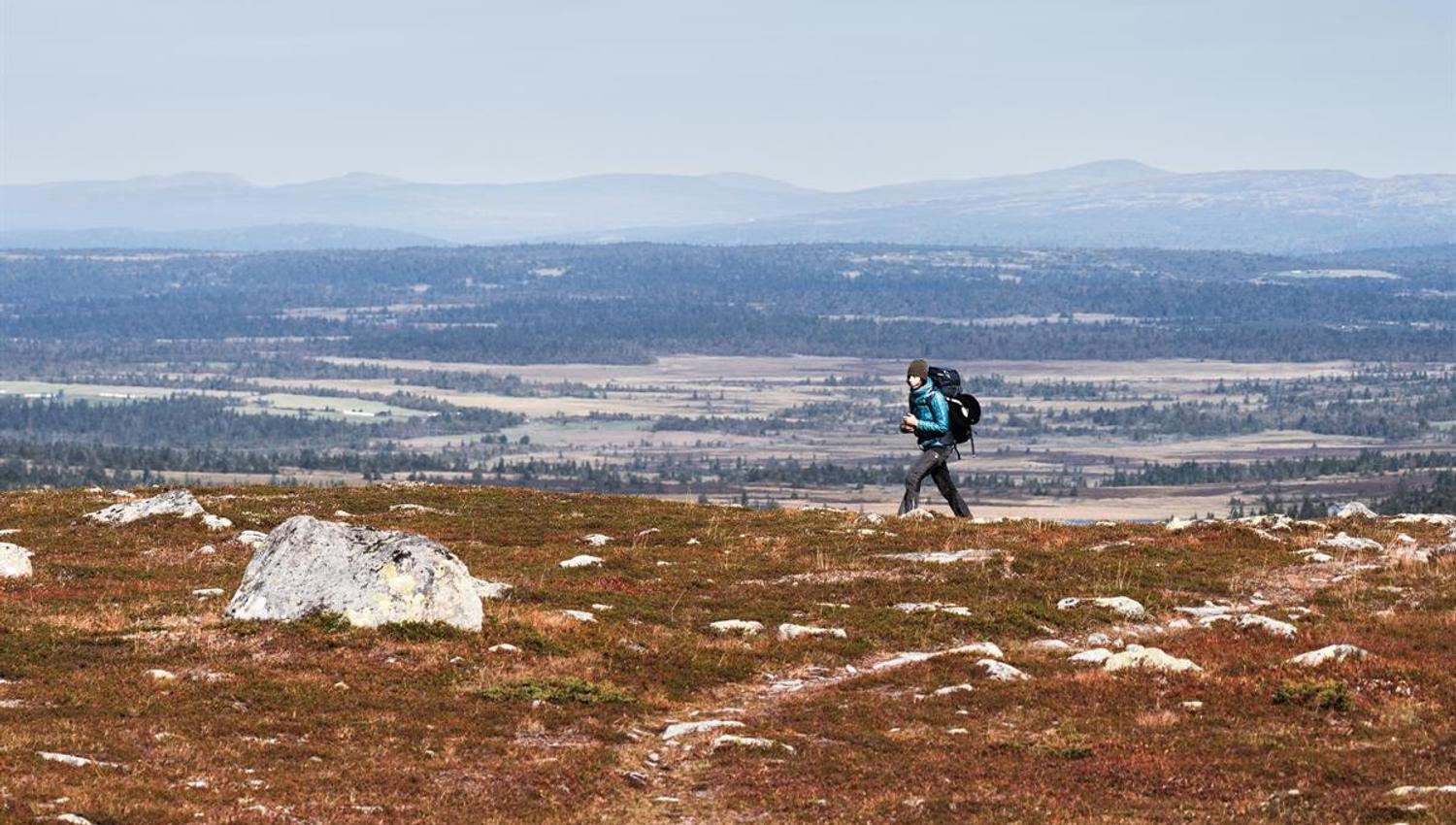 Person walking along a mountain ridge with views of valley and water