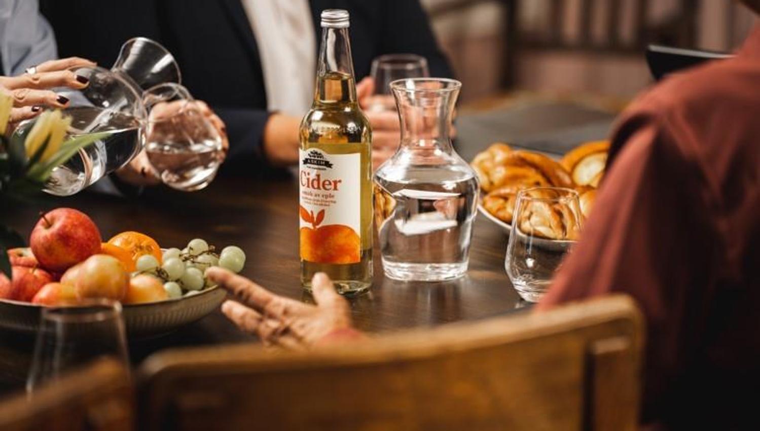 personer ved bord med frukt, kanelboller, cider og vann