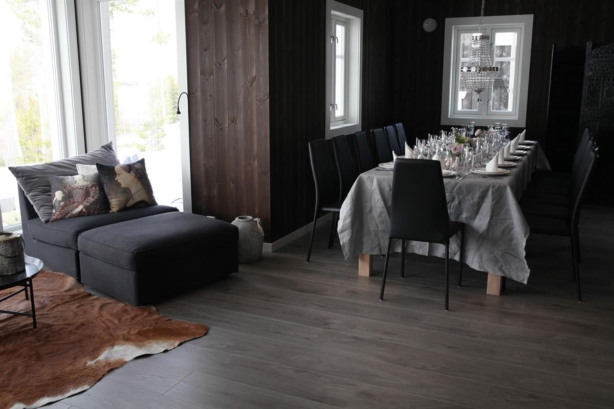 A living room with a dining table and sofa in a dark wood-paneled interior.