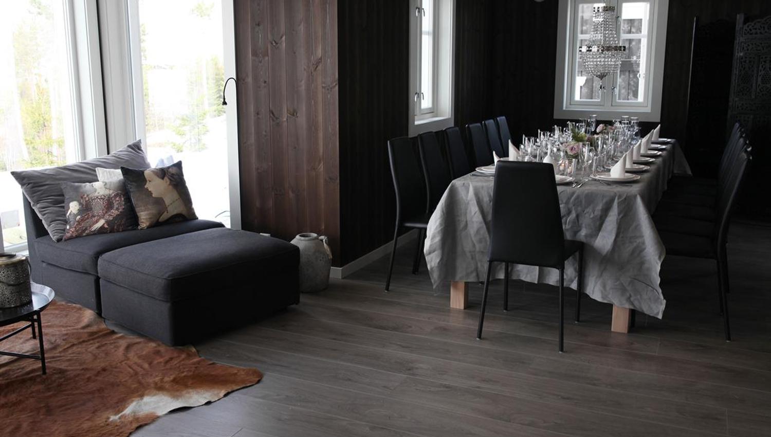 A living room with a dining table and sofa in a dark wood-paneled interior.