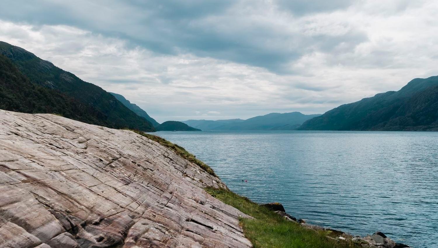 The fjord landscape surrounding Vingen, with ancient rock carvings on the rock surface in the foreground.