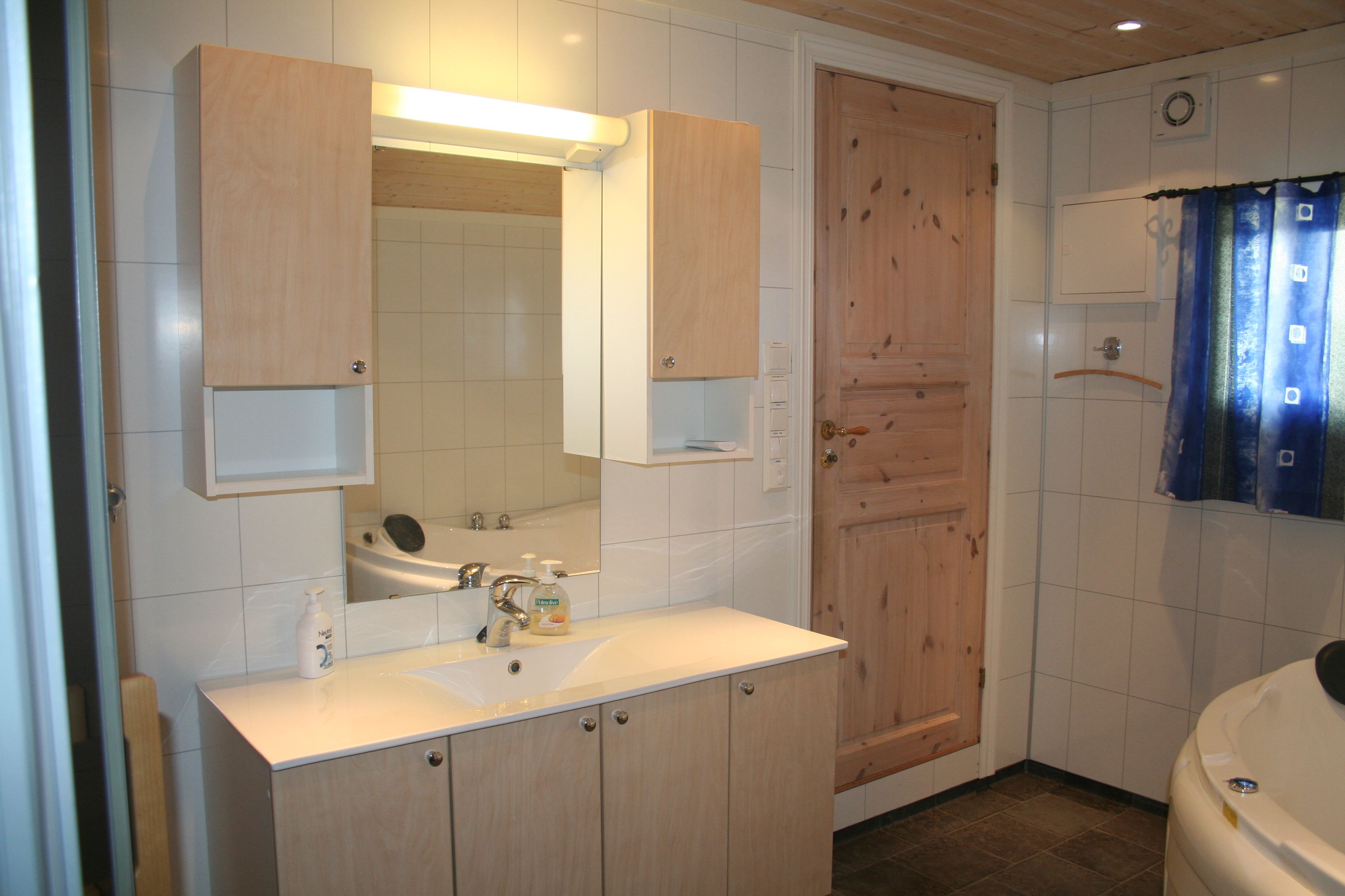 Bright and spacious bathroom with a large sink, mirror, and ample storage space.