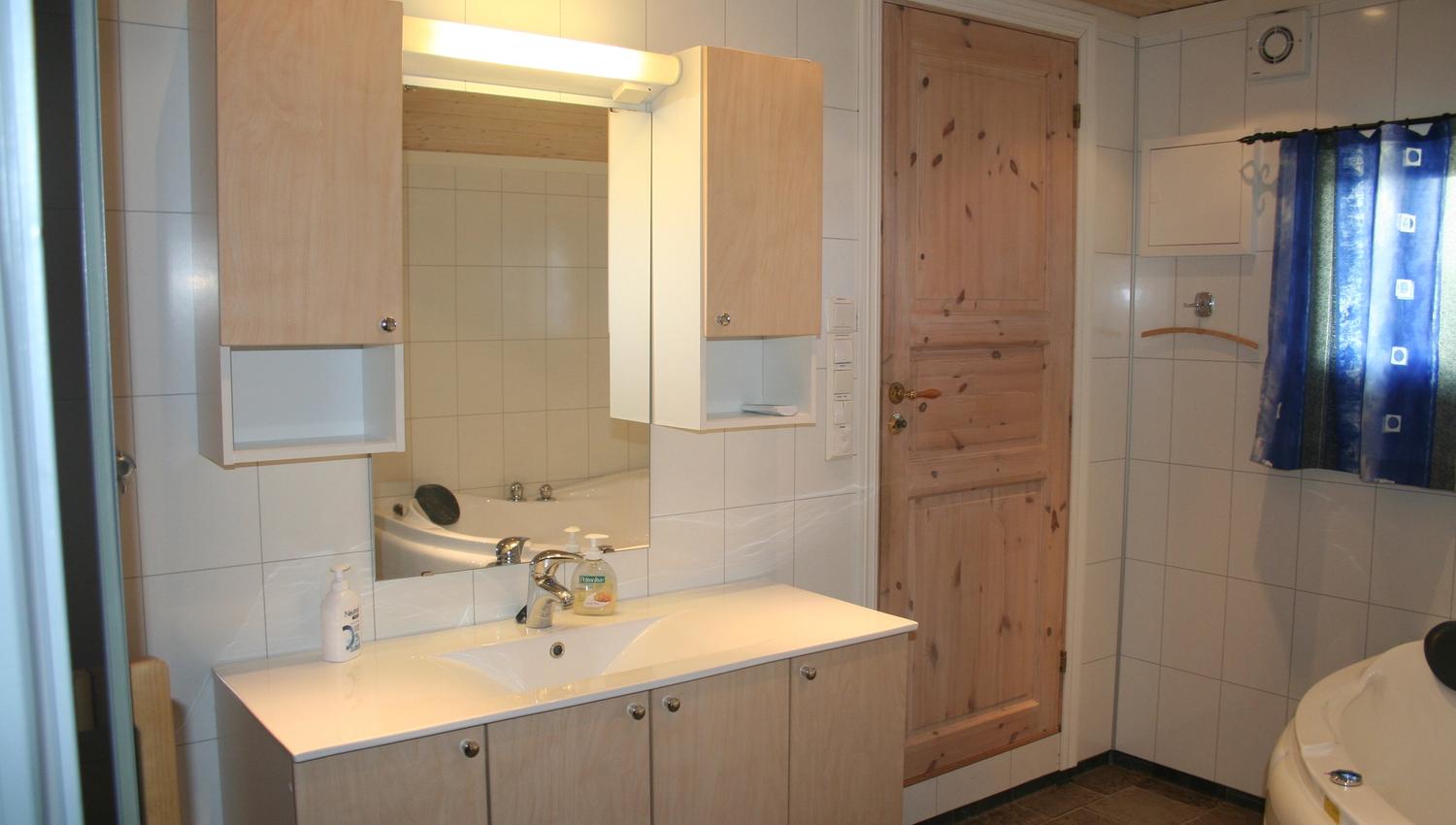 Bright and spacious bathroom with a large sink, mirror, and ample storage space.