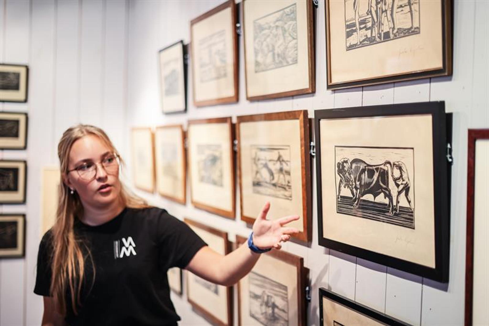 An employee shows a woodcut of «To menn holder en okse» (“Two men holding a bull.”)
