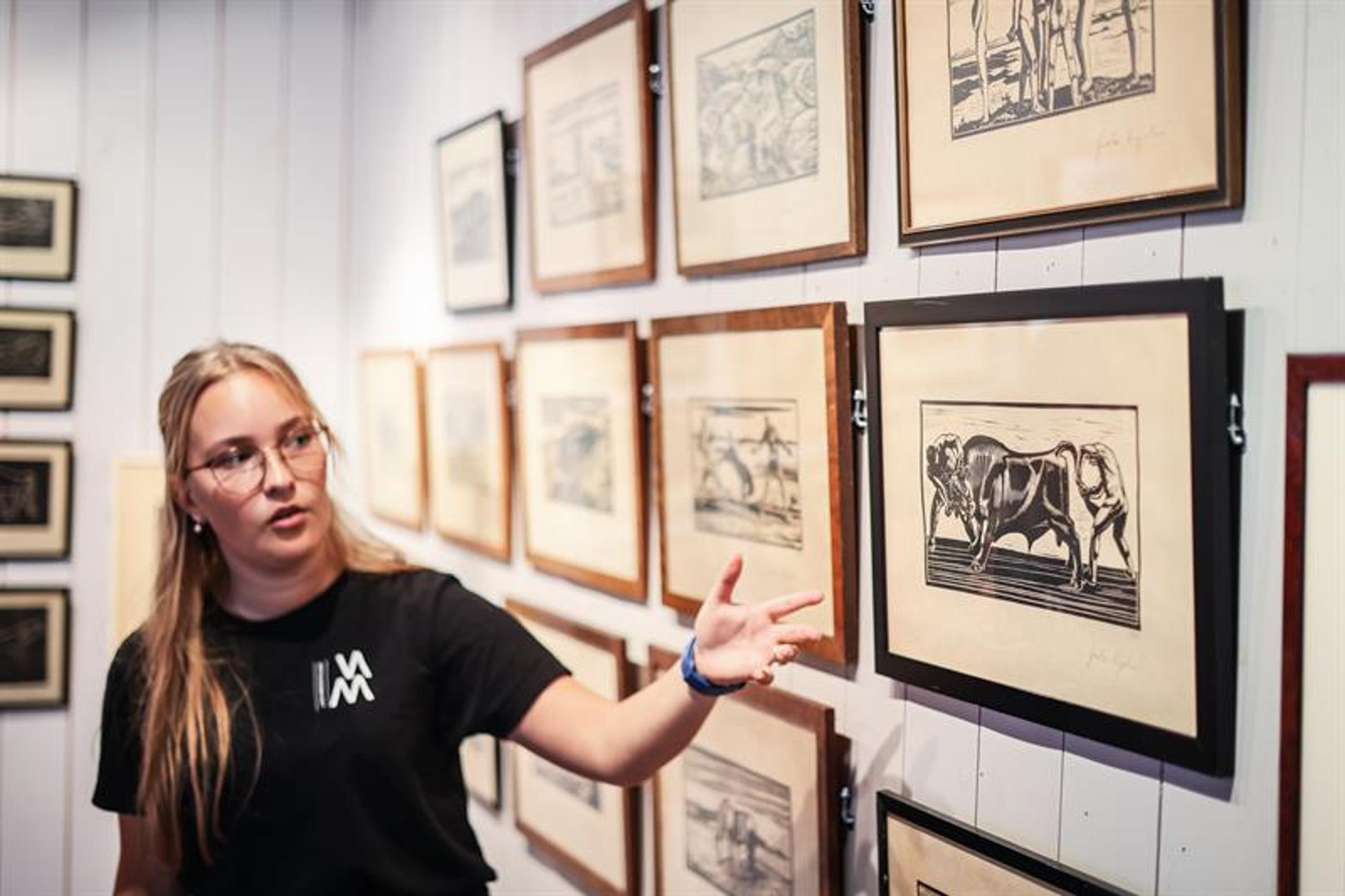 An employee shows a woodcut of «To menn holder en okse» (“Two men holding a bull.”)