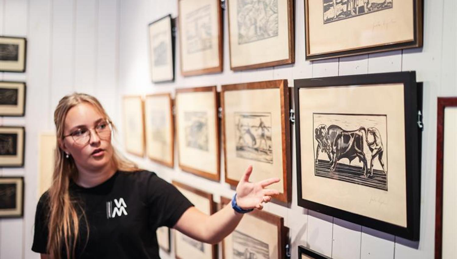 An employee shows a woodcut of «To menn holder en okse» (“Two men holding a bull.”)