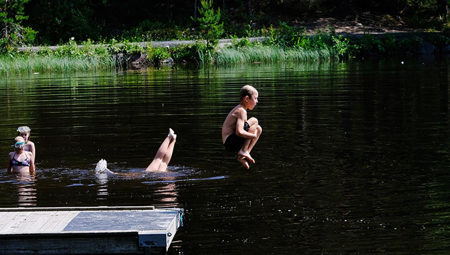 Gutt hopper fra bryggen i vannet på Tinnemyra, Notodden. Foto
