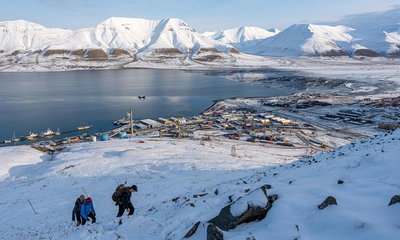 flere personer vandrer oppover fjellet i snødekt landskap