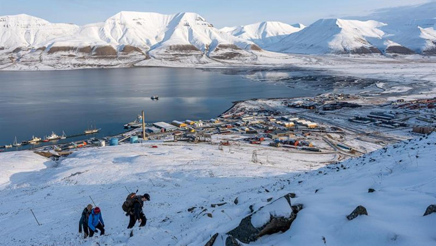 flere personer vandrer oppover fjellet i snødekt landskap