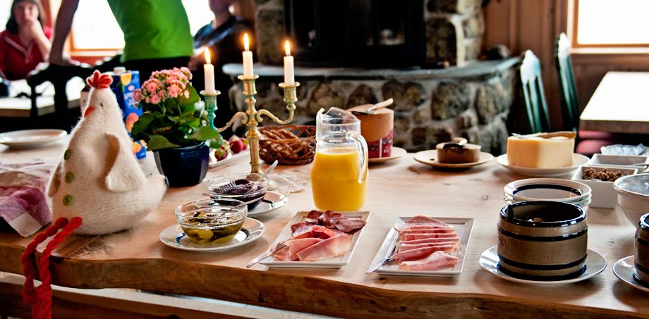 Breakfast table with candles, an easter chicken, orange juice and different bread spreads.