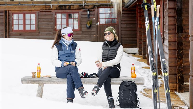 2 ladies with skis  chilling outside the hut