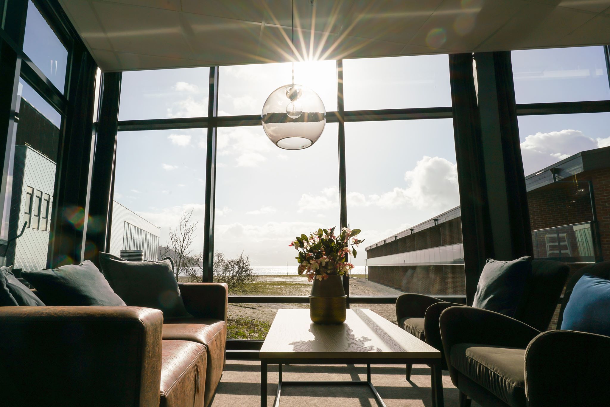 Bright and modern lounge area with large windows and sun rays streaming in.