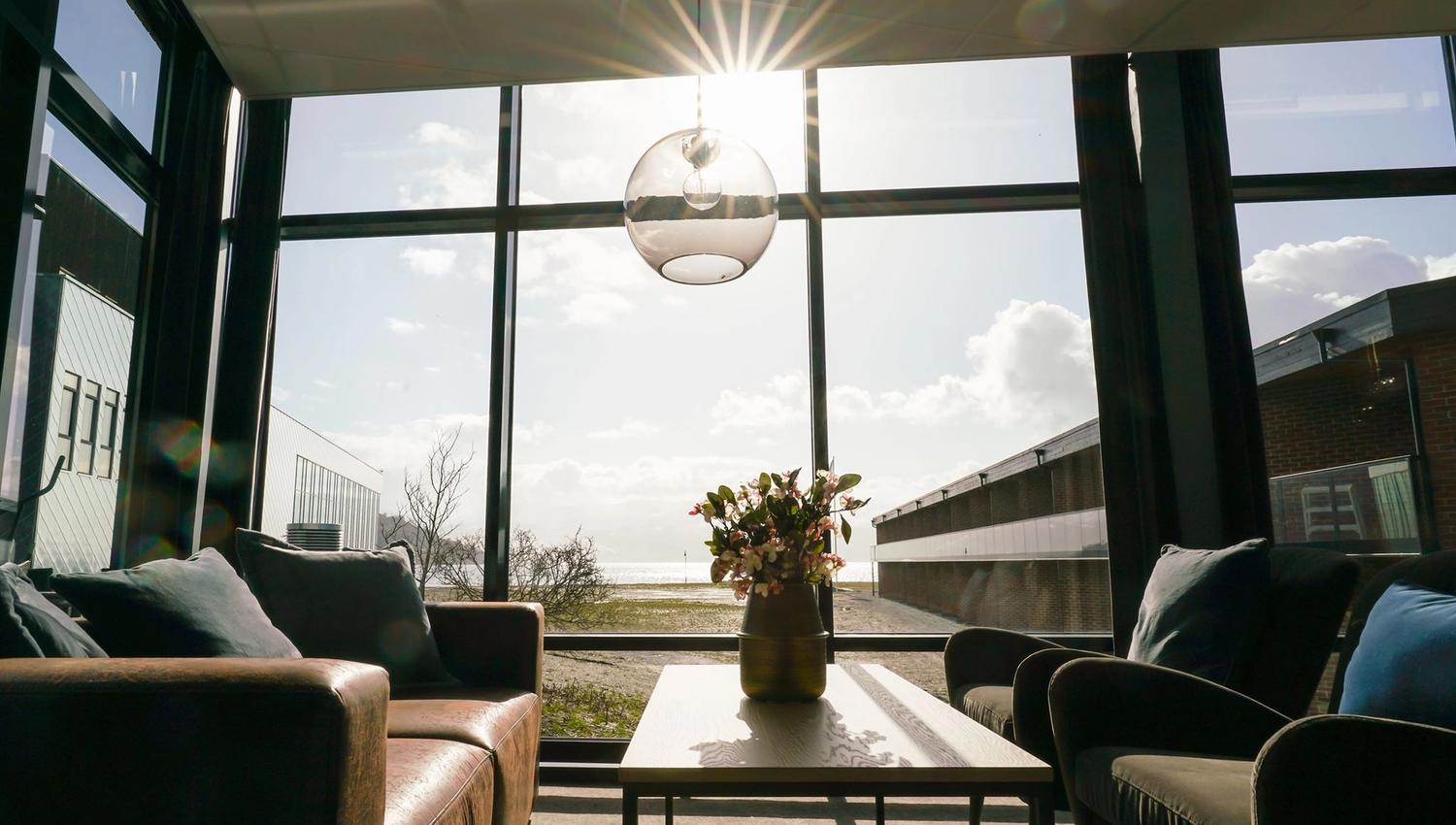 Bright and modern lounge area with large windows and sun rays streaming in.