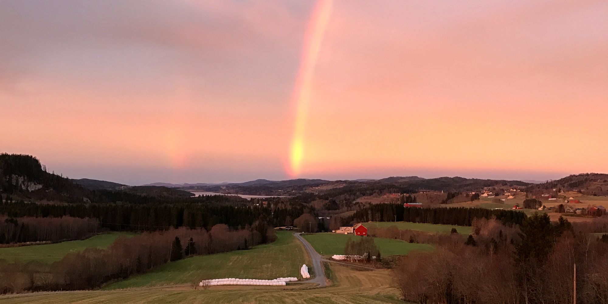 Troset i Levanger Kommune: Utsikt fra gården med regnbue og solnedgang