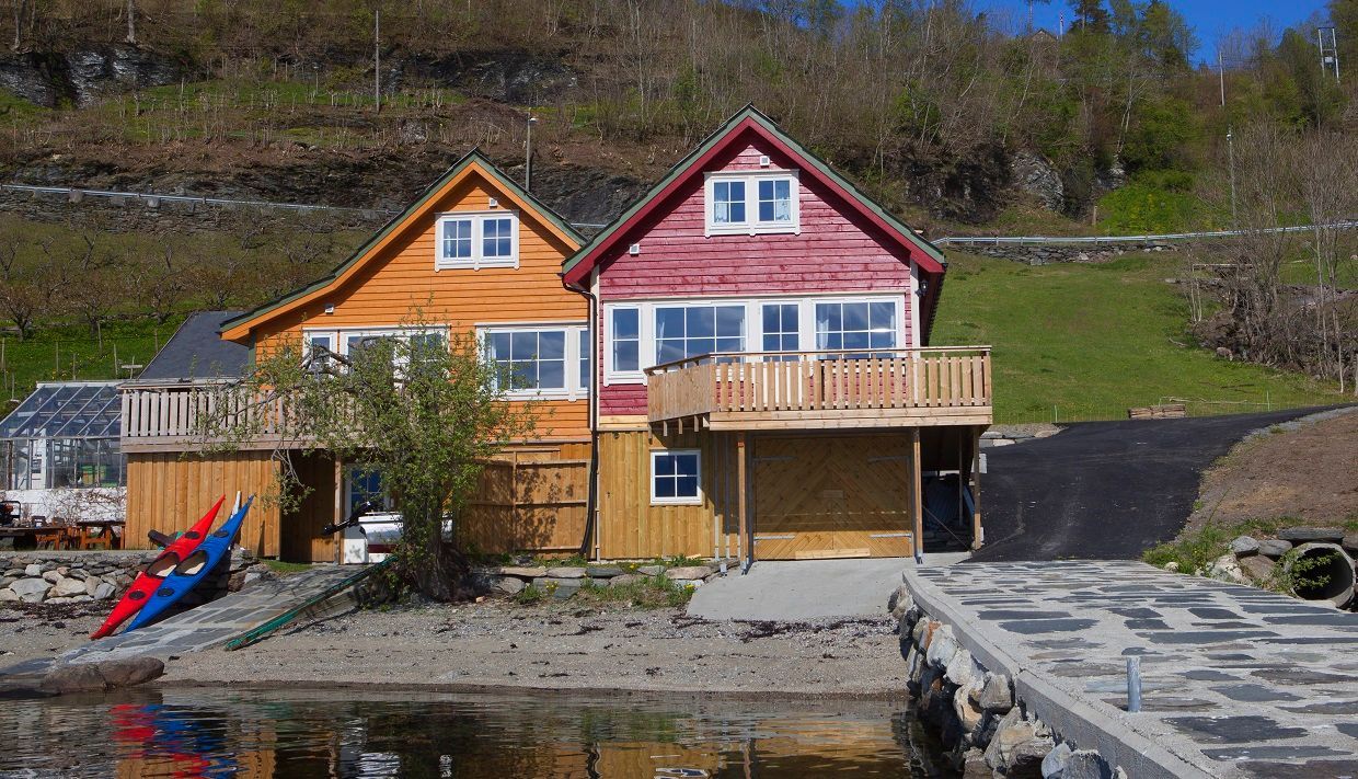 Red and yellow boathouses with terrace by the sea – perfect for a holiday stay in Hardanger.