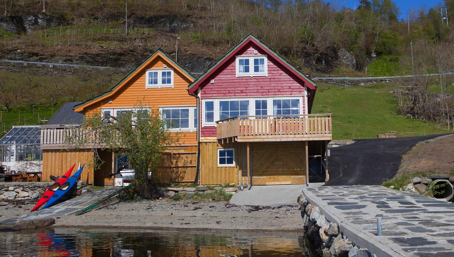 Red and yellow boathouses with terrace by the sea – perfect for a holiday stay in Hardanger.