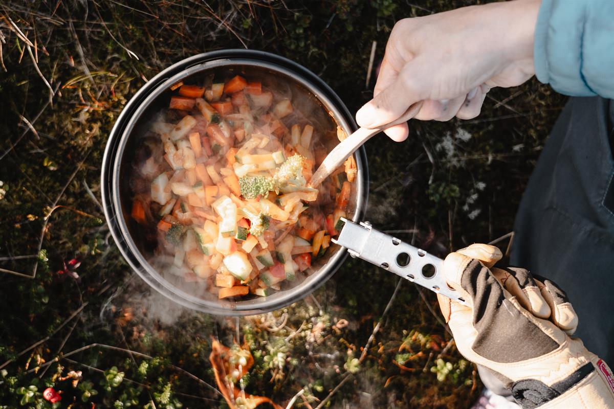 Pot with food over a fire in the forest.