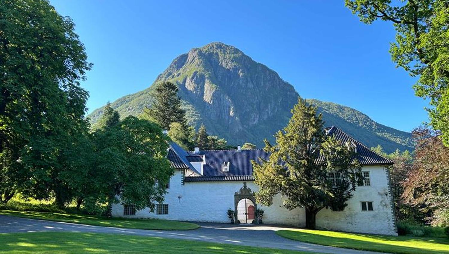 Sommarstemning ved Baroniet Rosendal i Kvinnherad, med parklandskap og klassisk arkitektur.