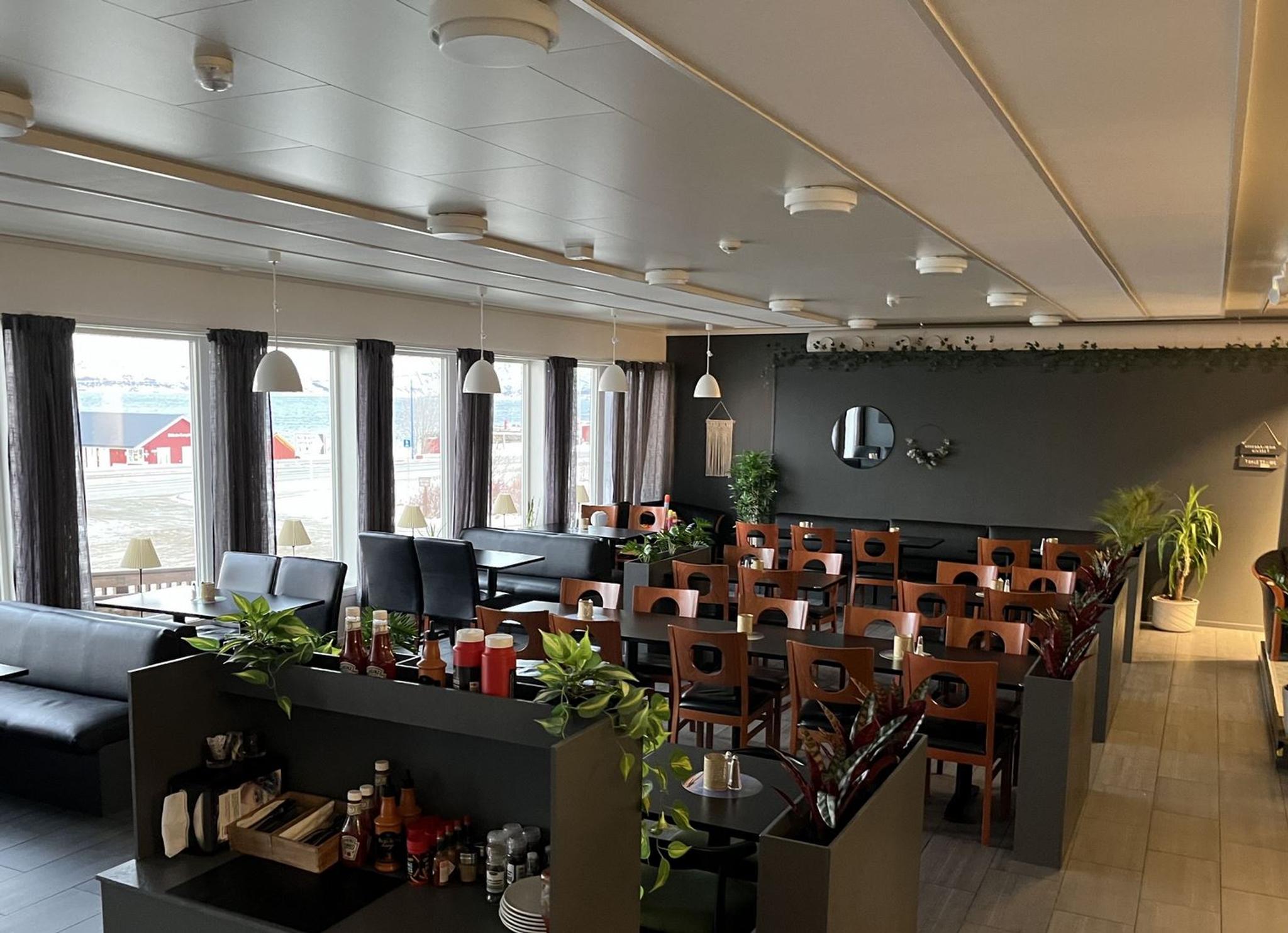 The interior of Arken Bistro with table and chairs, some green plants in between