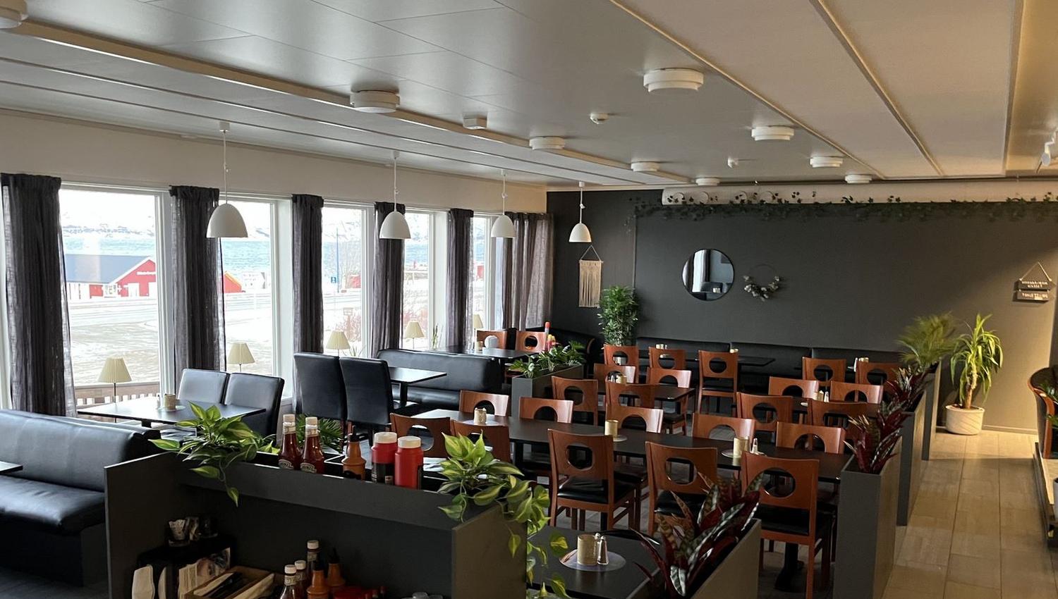 The interior of Arken Bistro with table and chairs, some green plants in between