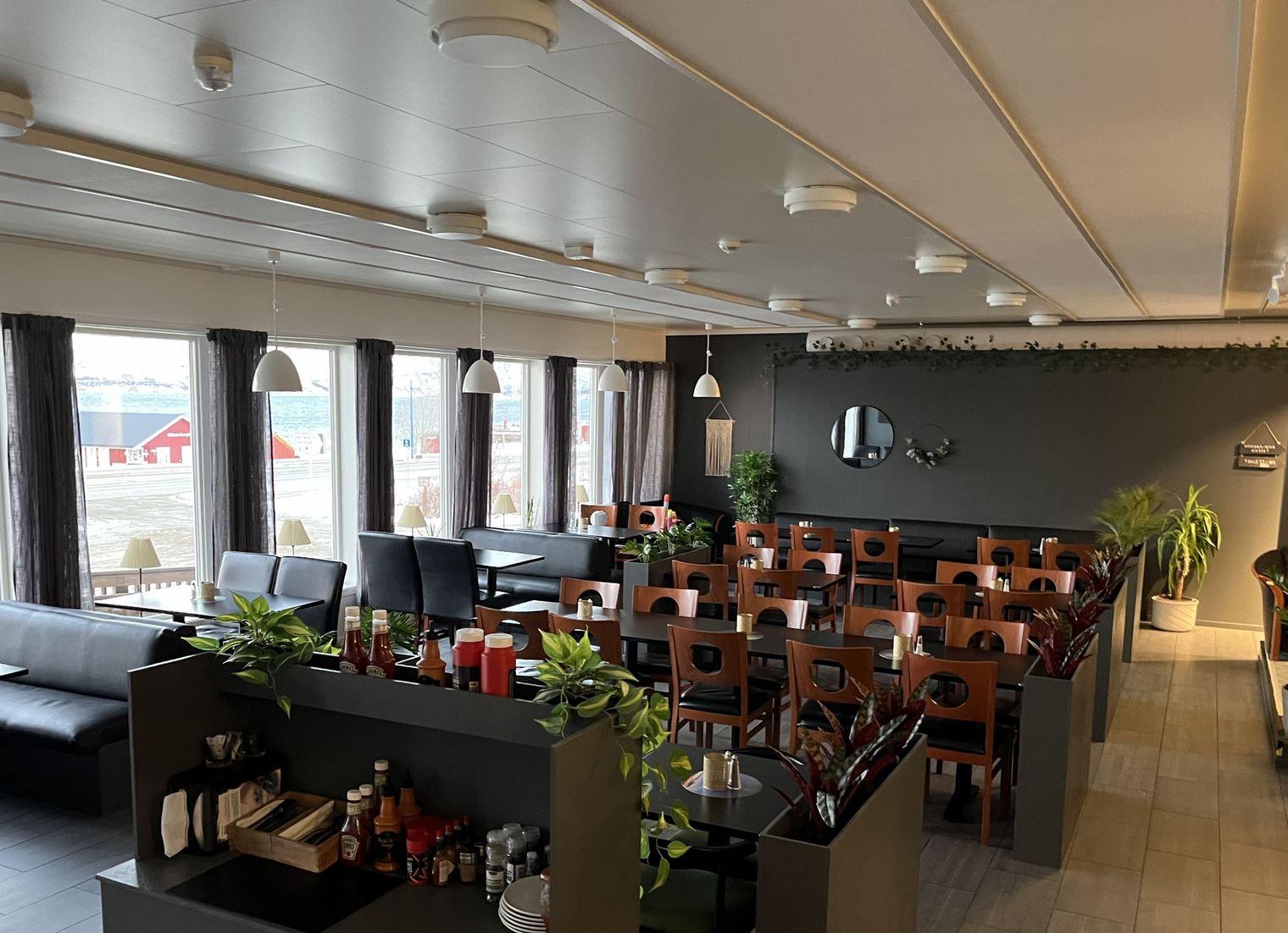 The interior of Arken Bistro with table and chairs, some green plants in between
