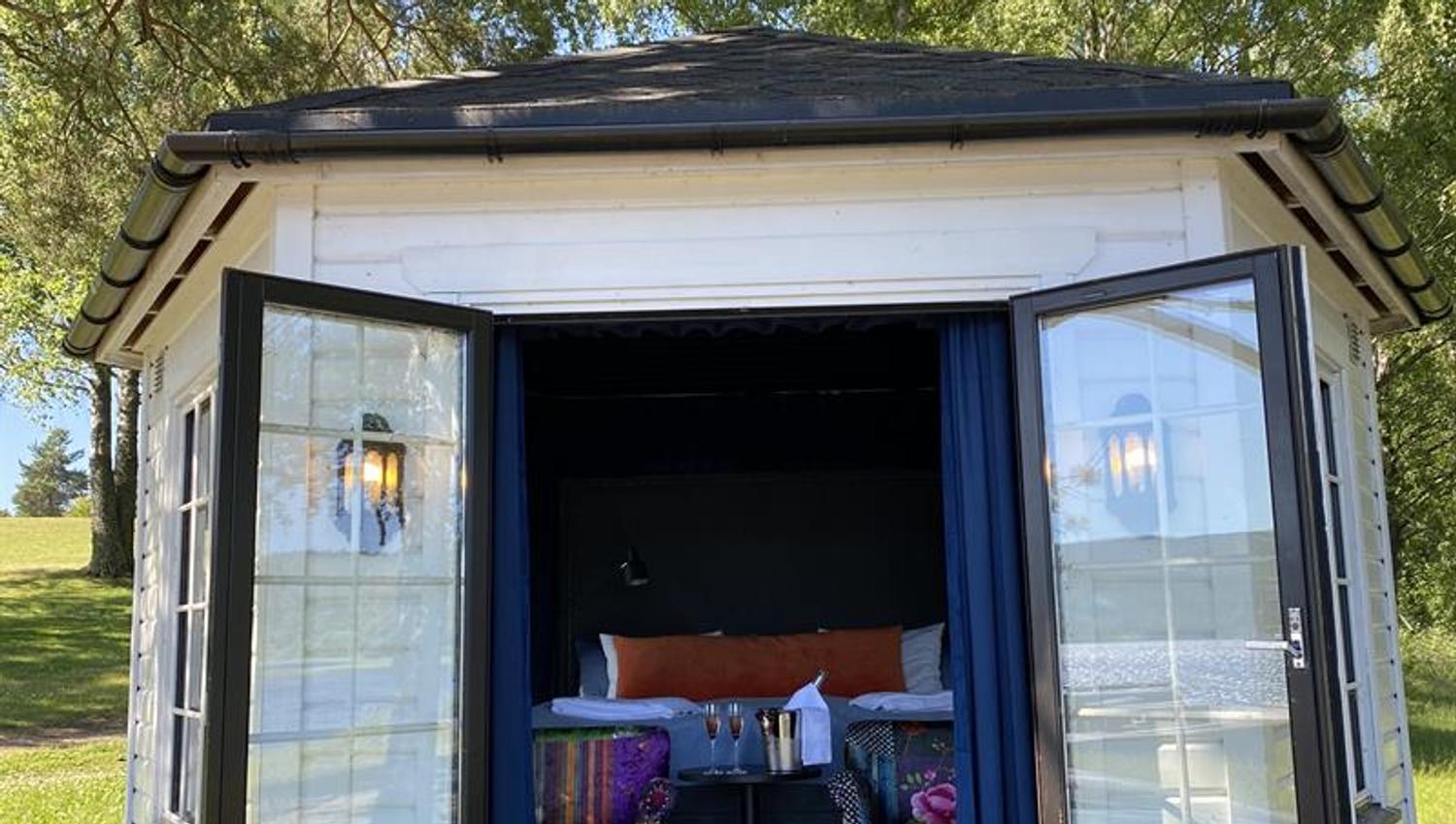 strandhus sett utenfra med stoler og seng