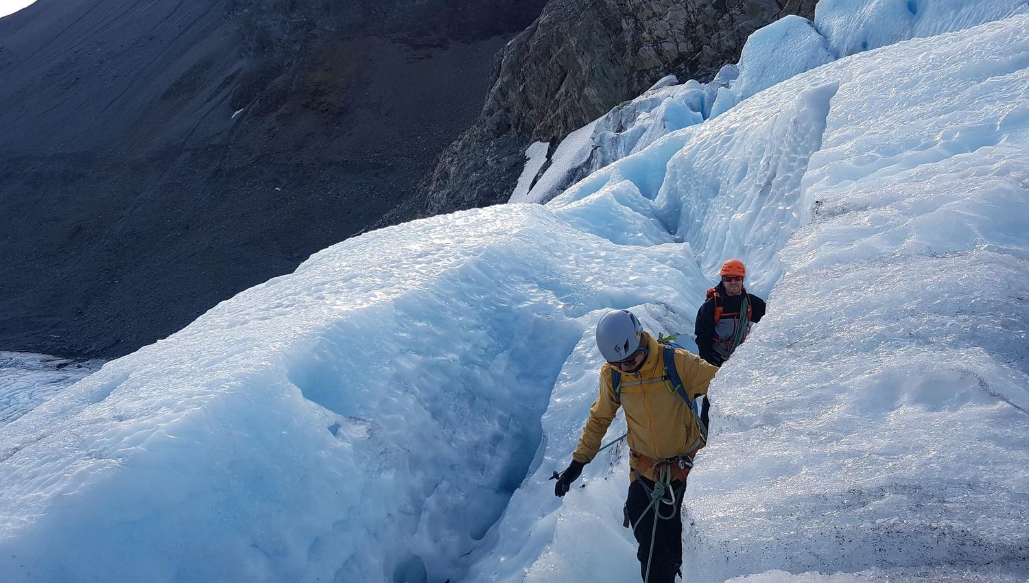 Two persons walking on a glacier.
