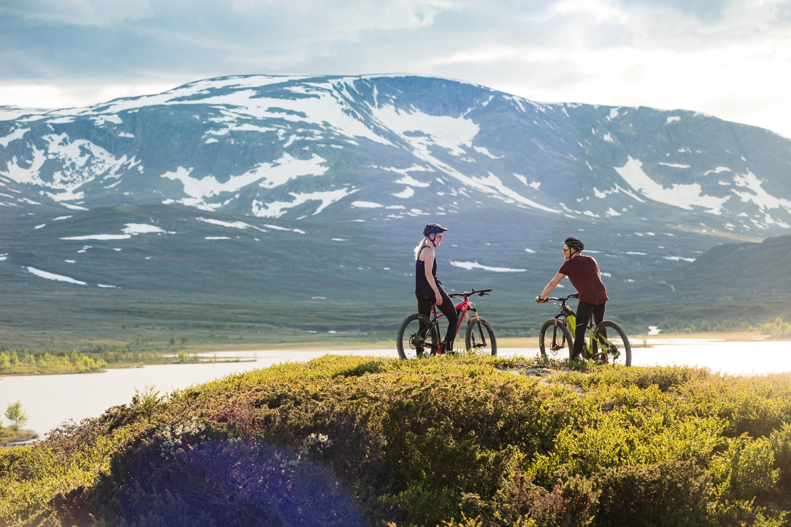 Two cyclists take a break in front of the Budalen lake in tremendous Hallingskarvet national park  