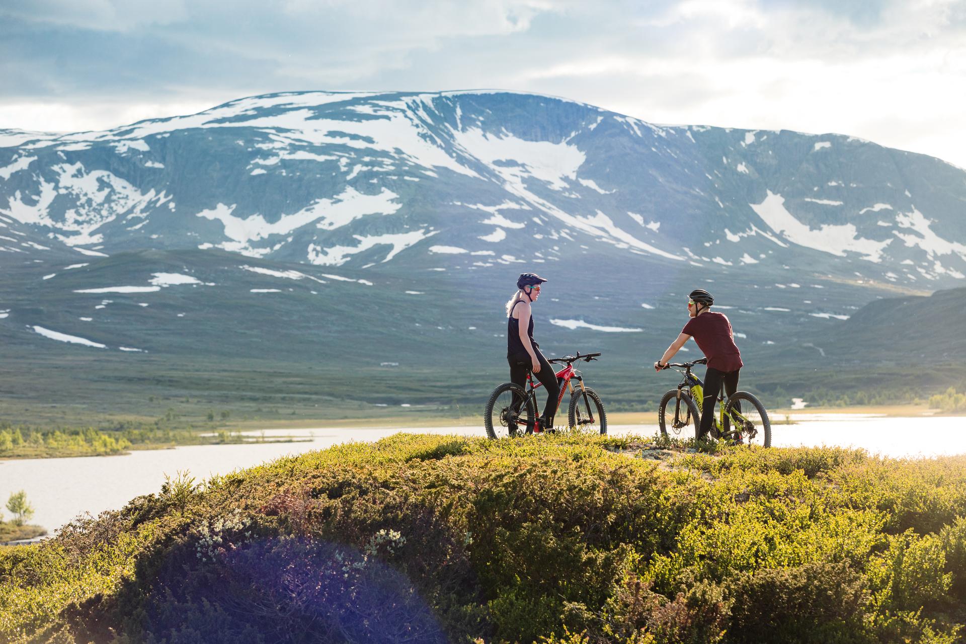 Two cyclists take a break in front of the Budalen lake in tremendous Hallingskarvet national park