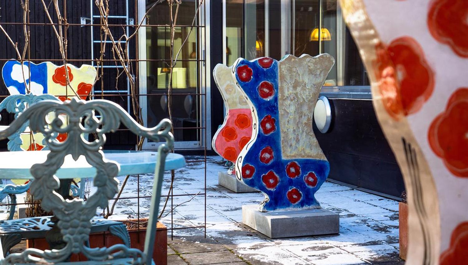 Colorful outdoor sculptures arranged in a courtyard next to a building.