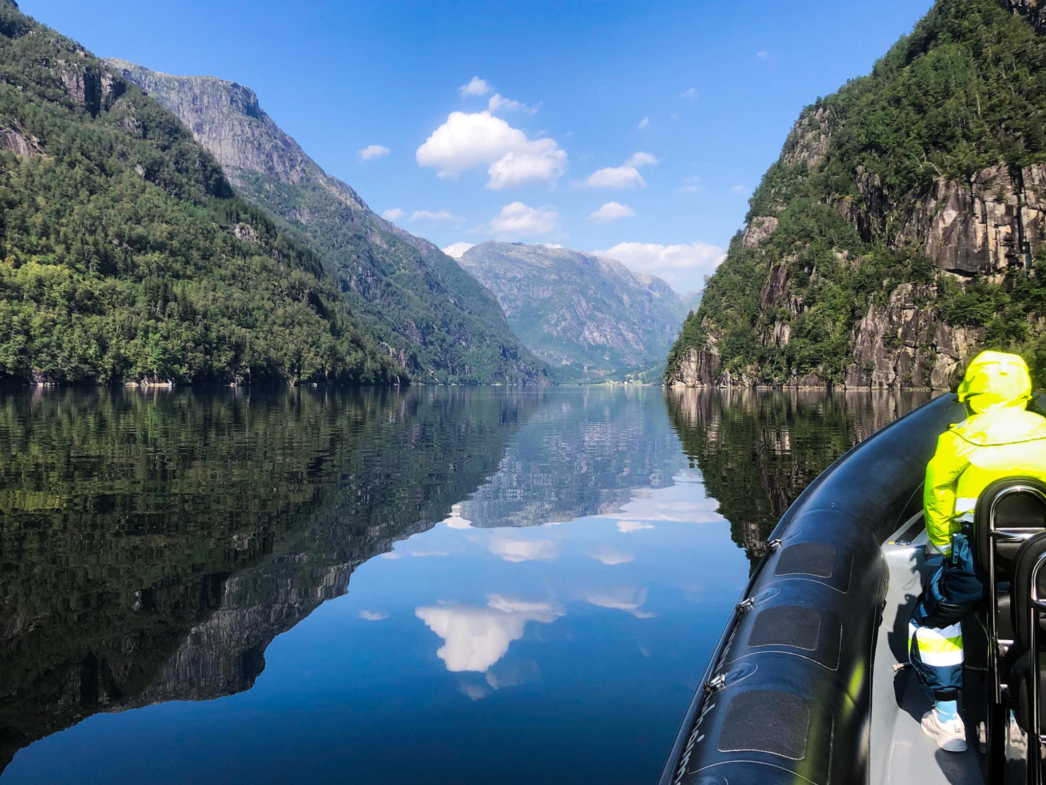 A mirror-like fjord surrounded by majestic mountains, viewed from a RIB boat on the Norheimsund RIB Seafari in Hardanger.