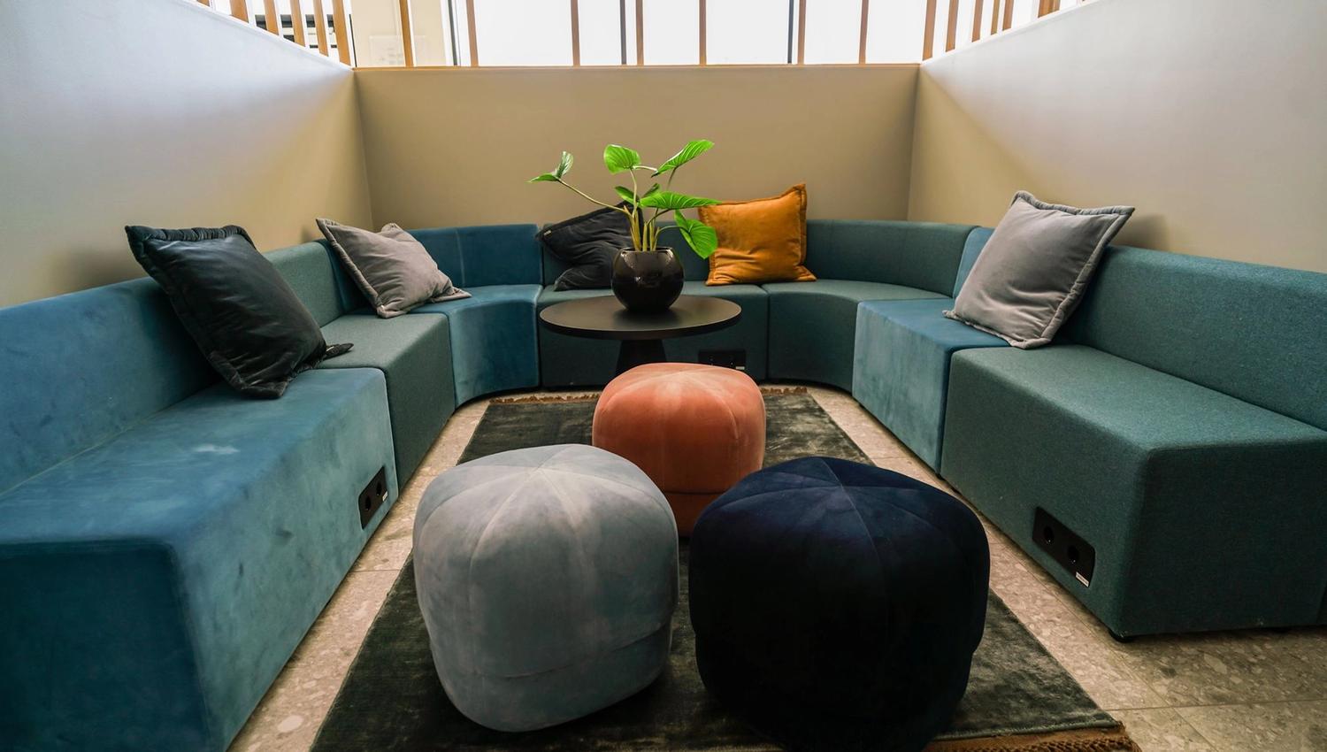Relaxing seating area with a blue sofa and colorful poufs, ideal for unwinding.