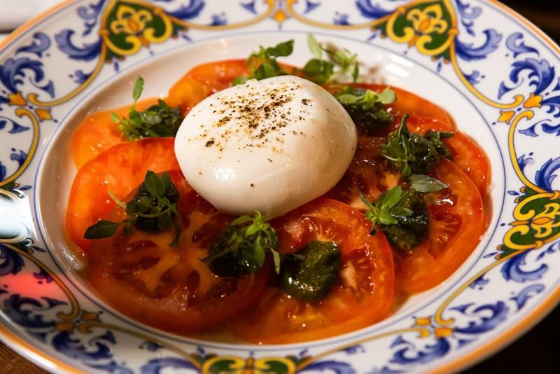 Detail of mozarella cheese on top of tomato slices on a plate