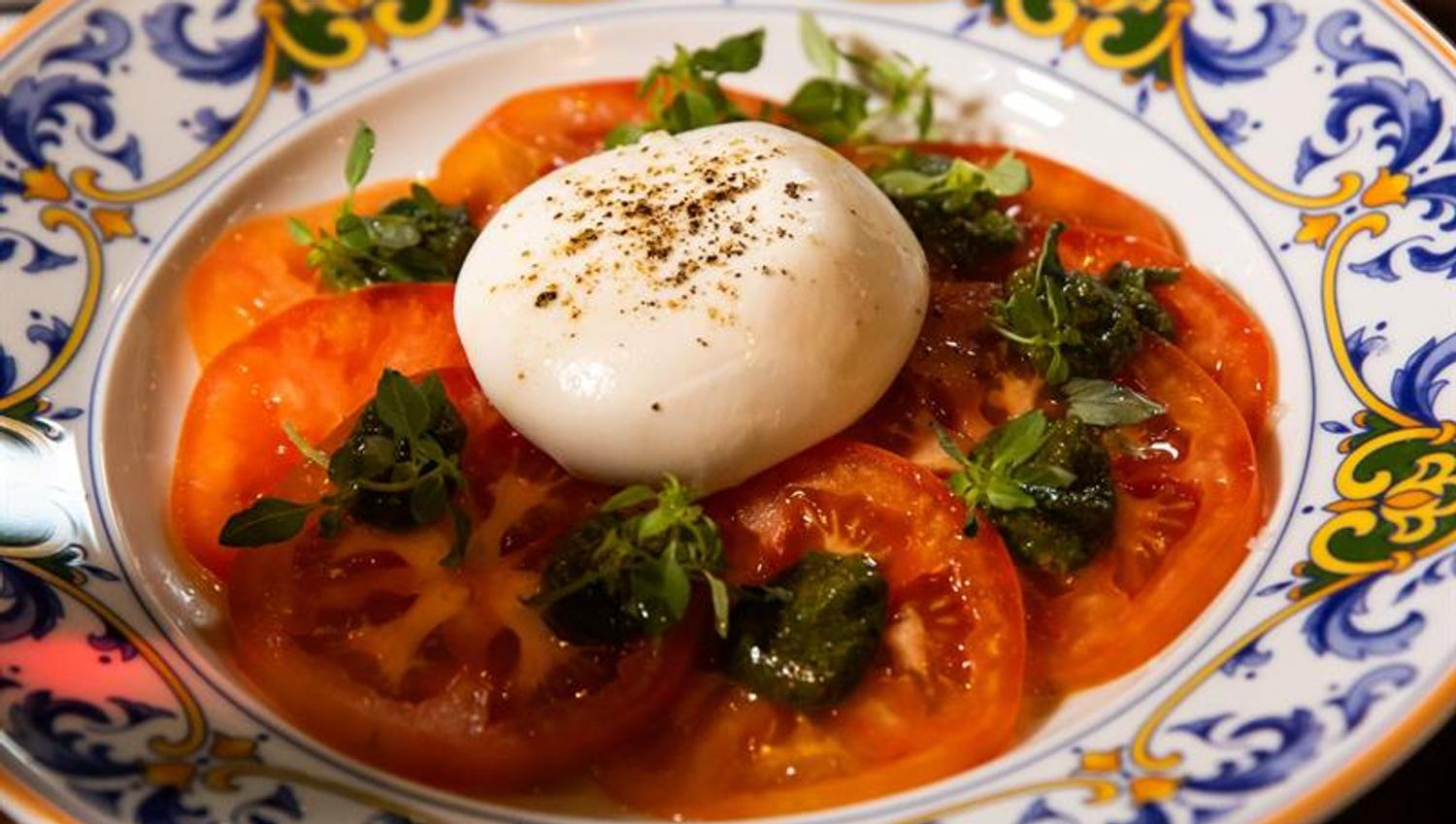 Detail of mozarella cheese on top of tomato slices on a plate