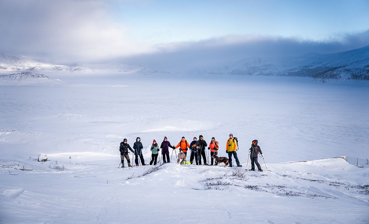 Group snowshoeing with a stunning view of the snow-covered Hardangerfjord.