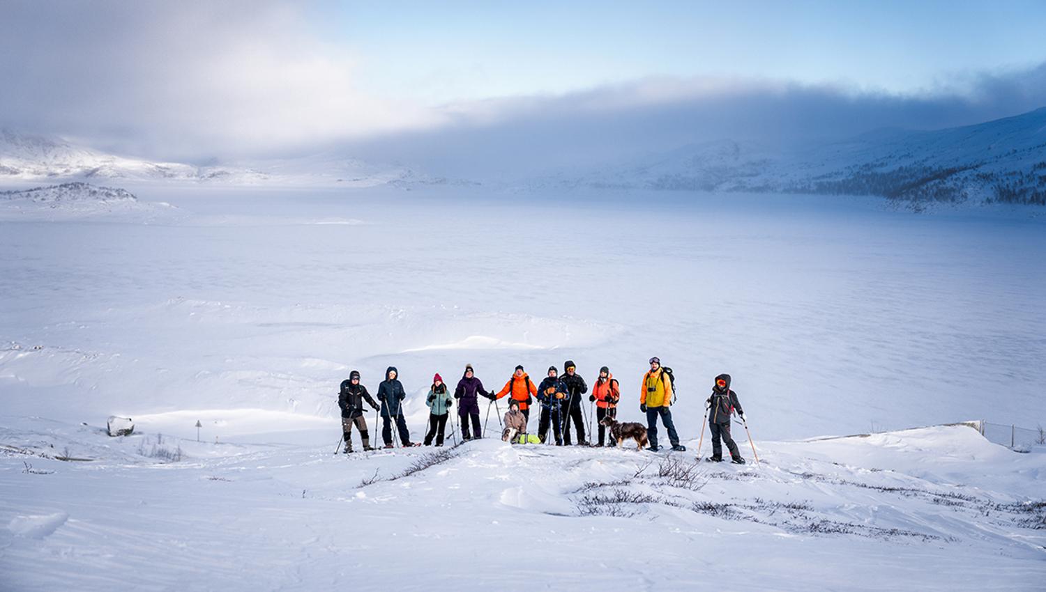 Group snowshoeing with a stunning view of the snow-covered Hardangerfjord.